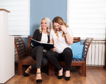 smiling women looking at book on bench